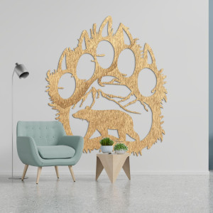 Ein hölzernes Bild eines Bärenfußabdrucks, in das die Silhouette eines Bären geschnitzt ist, der unter den Bergen läuft.