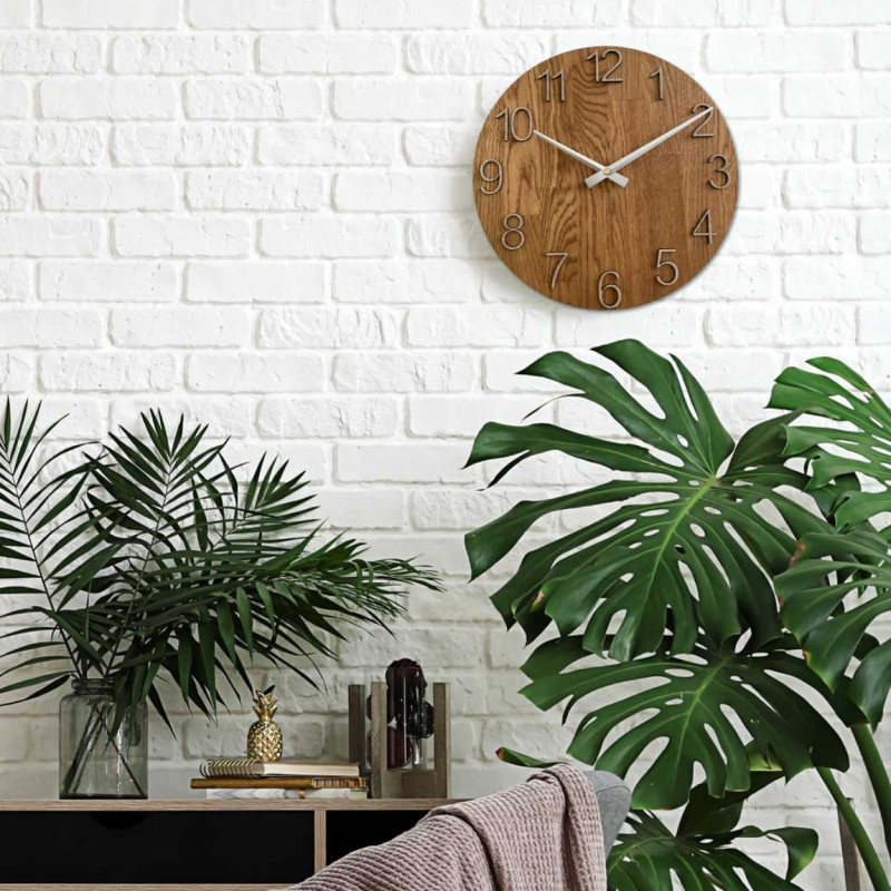 Runde Uhr mit dekorativem Ausschnitt in der Mitte und zartem Holzmuster.